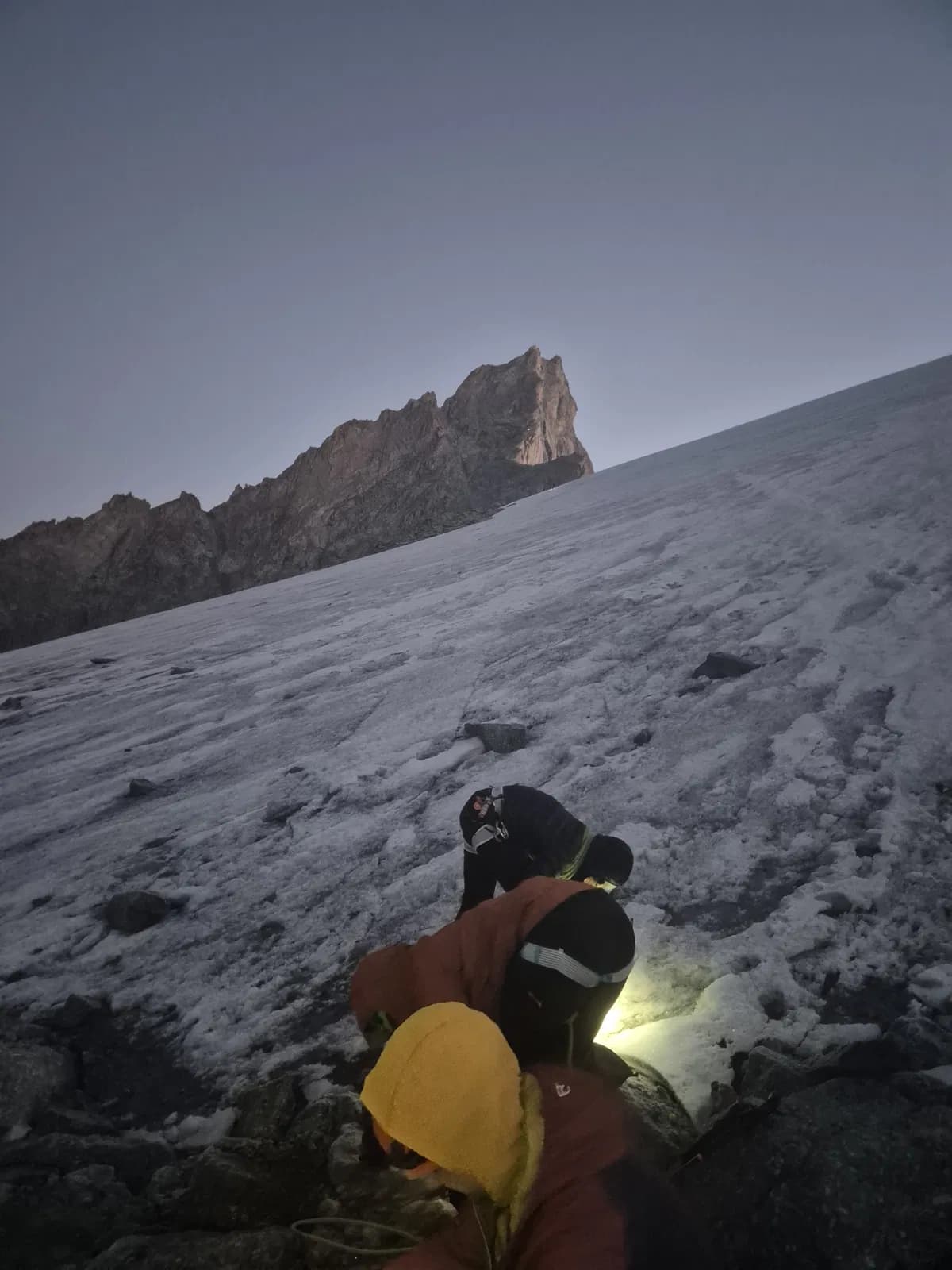 Steigeisen anlegen am Firnfeld im Aufstieg zum Zinalrothorn mit Gipfel im Hintergrund