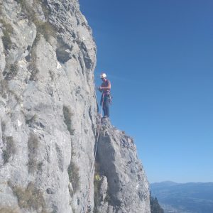 Klettern an der Martinswand. Eine Person steht auf einem Felsvorsprung. Im Hintergrund sieht man das Inntal und Innsbruck